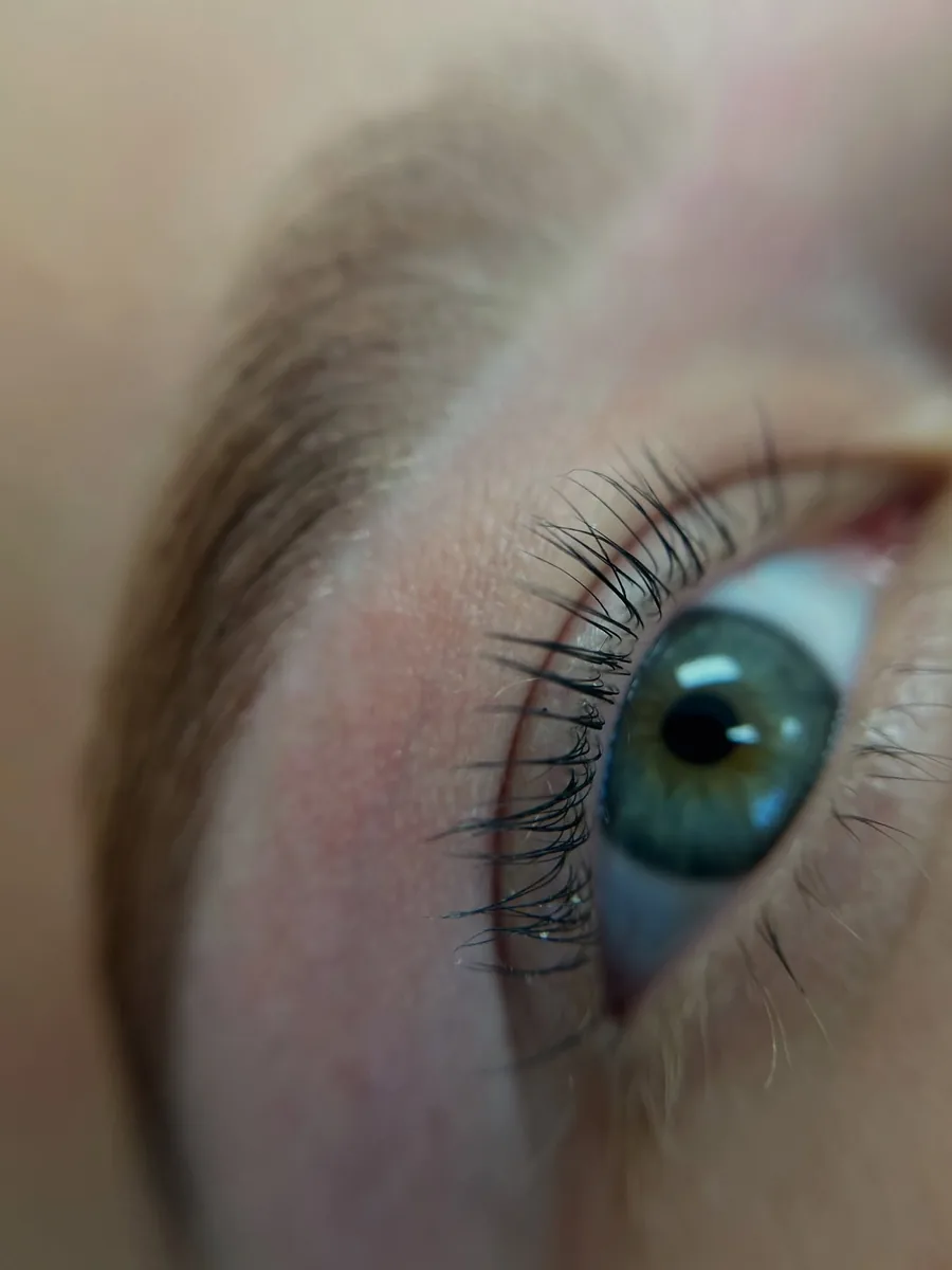 Laminated brows and lifted lashes on blue-grey eyes